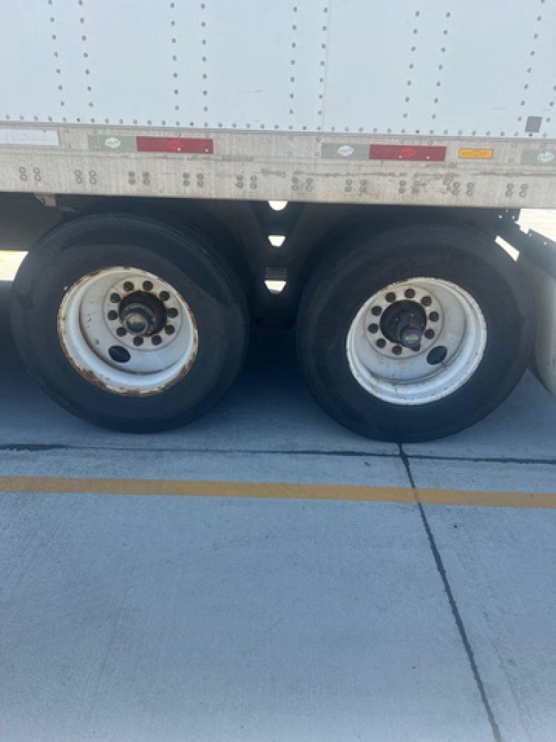 Two trailer tires on a utility van side view with wheel rims and a portion of the cargo body above; no legible model text visible on image.