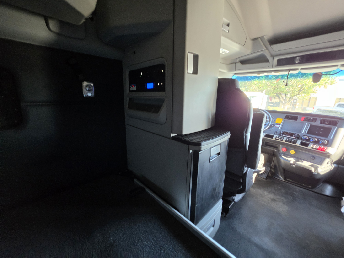 Interior of a Kenworth T680 cab showing sleeper area with cabinetry and dash visible in the background.