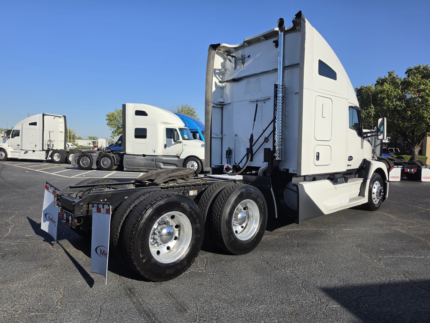 Kenworth T680 conventional sleeper tractor chassis and cab side view showing rear triple axle and fifth wheel with rear mud flaps.