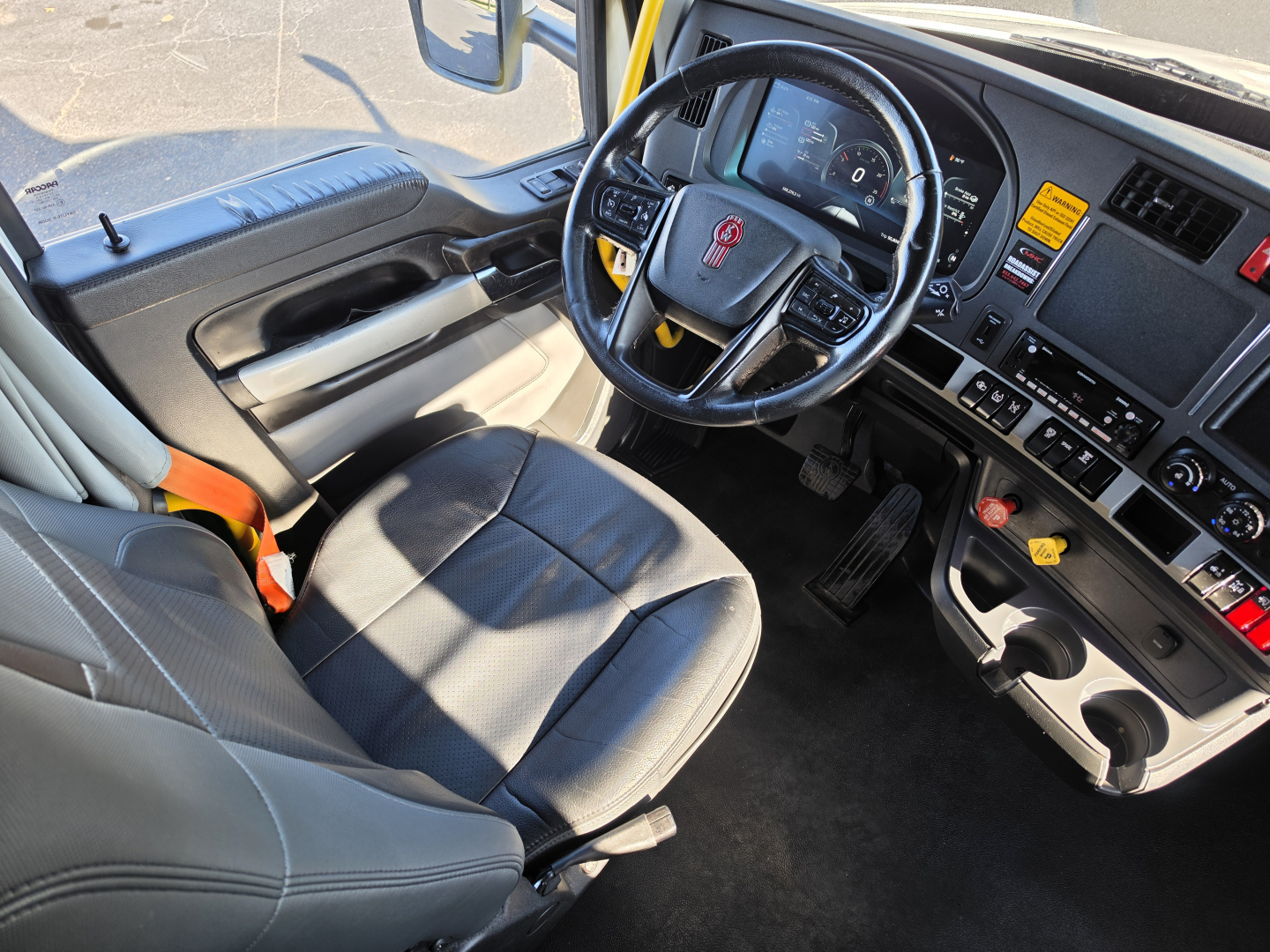 Kenworth T680 truck cab interior showing steering wheel, dashboard with controls, and driver seat; visible VIN and stock data not on image, but interior layout includes center console and cup holders.