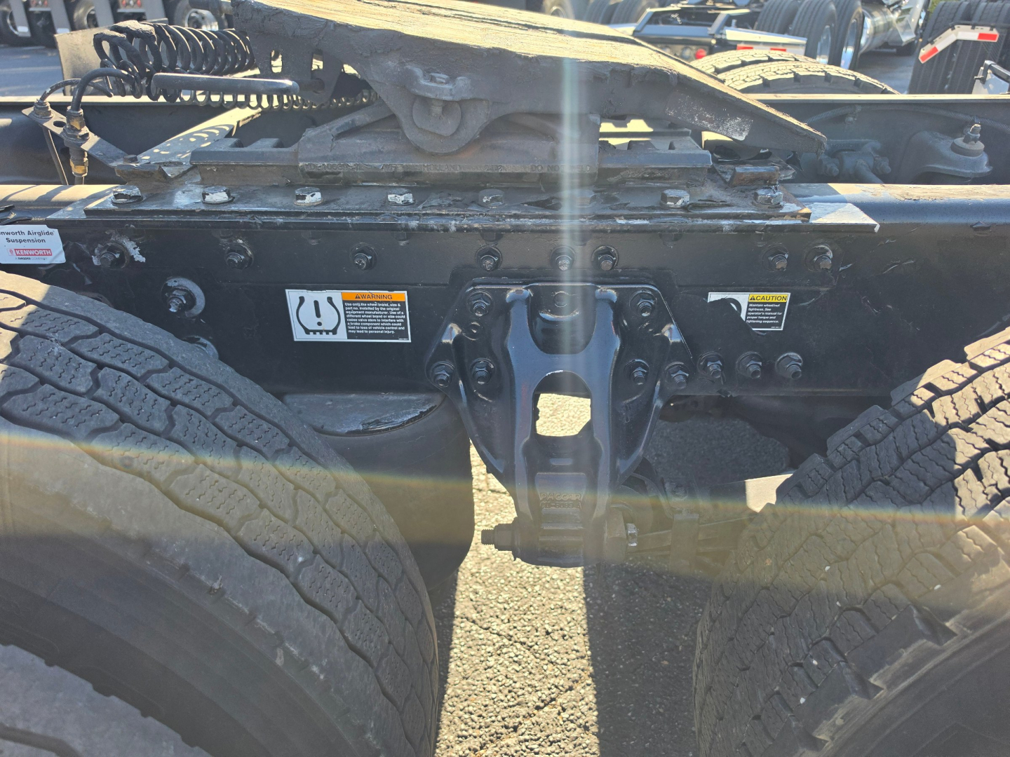 Kenworth T680 undercarriage showing rear chassis, suspension, and drive axle area with tires and frame components.