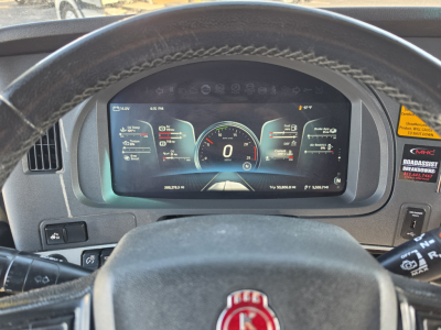 Dashboard of a 2023 Kenworth T680 showing digital instrument cluster with 0 mph, steering wheel, and driver’s view.