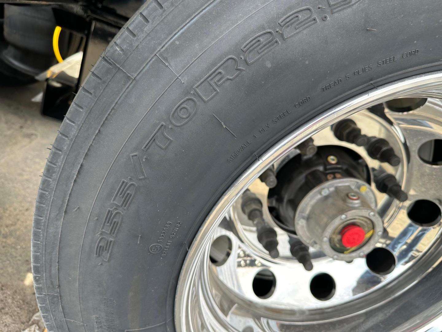 Lowboy trailer wheel and tire close-up showing stamped lettering on tire sidewall.