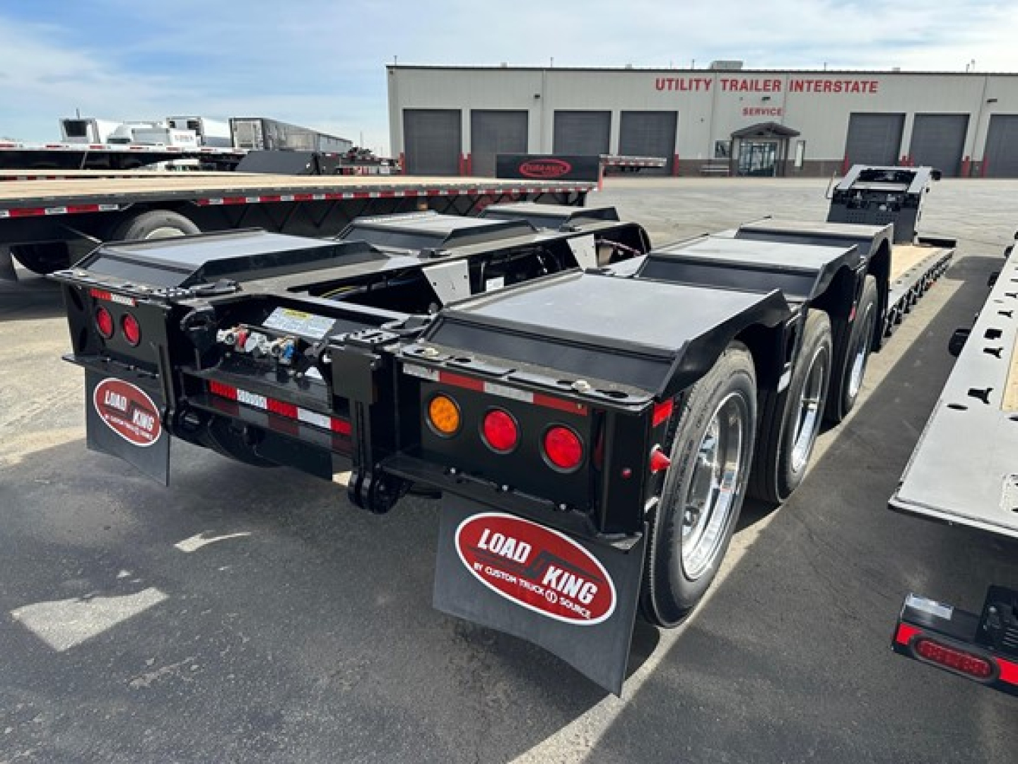 Load King lowboy trailer rear view showing dual axles, rear lights, mud flaps, and gooseneck hitch area.