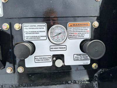 Lowboy trailer front control panel showing height control operation labels, gauge, and knobs; warning and operation stickers labeled ‘Height Control Operation’ and ‘Third Axle’ with dial in center.