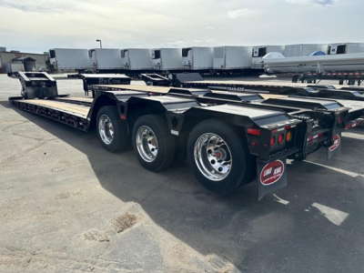 Load King lowboy trailer with multiple axles and polished wheels, showing rear and side profile with reflective black frame and trailer parts.