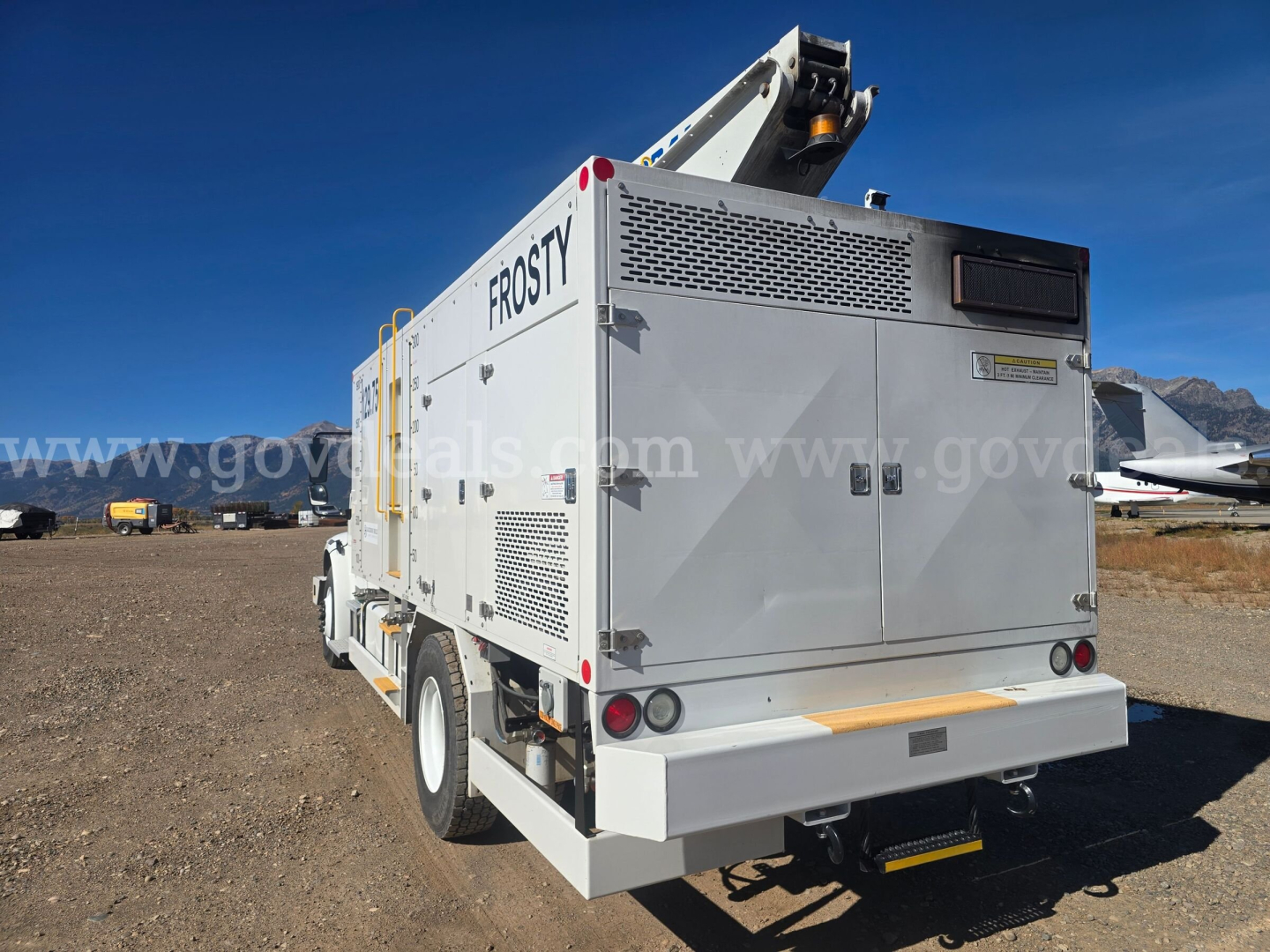 Back view of a Freightliner 2200SEB service truck with large white utility body, branding 'FROSTY' and various access panels, in a desert lot.