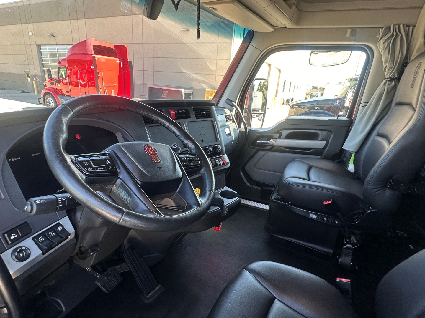 Kenworth T680 cab interior with steering wheel, dashboard, and driver seat; visible controls and center console.