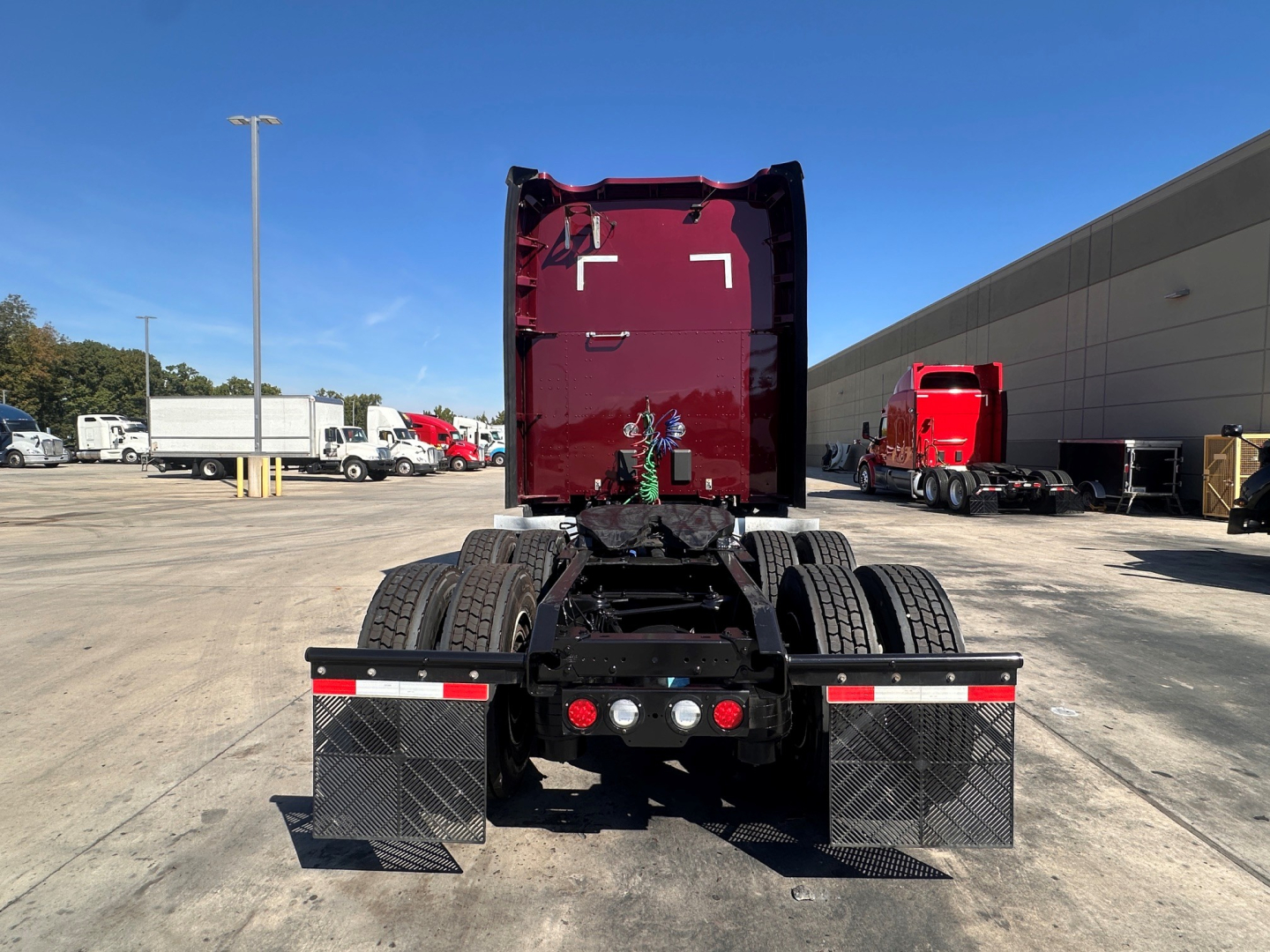 Kenworth T680 rear view showing fifth wheel and dual rear axles with mud flaps and metal step rails.