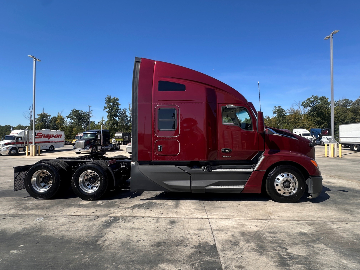 Kenworth T680 tractor in glossy red, side view showing sleeper cab, dual rear axles, and chrome wheels; VIN and stock not visible in image.