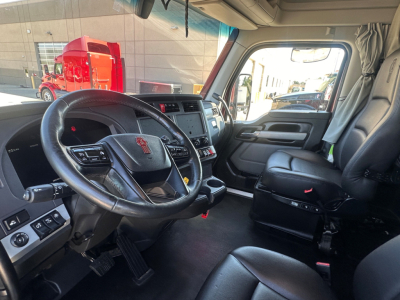 Kenworth T680 cab interior with steering wheel, dashboard, and driver seat; visible controls and center console.