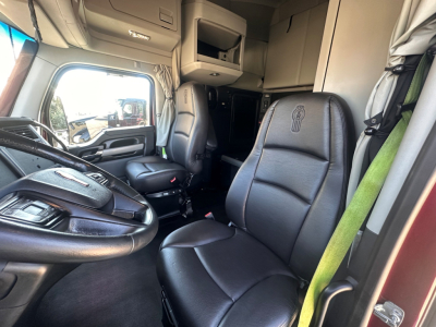 Kenworth T680 interior cabin with driver and passenger seats, dashboard, overhead storage, and bunk area in view.