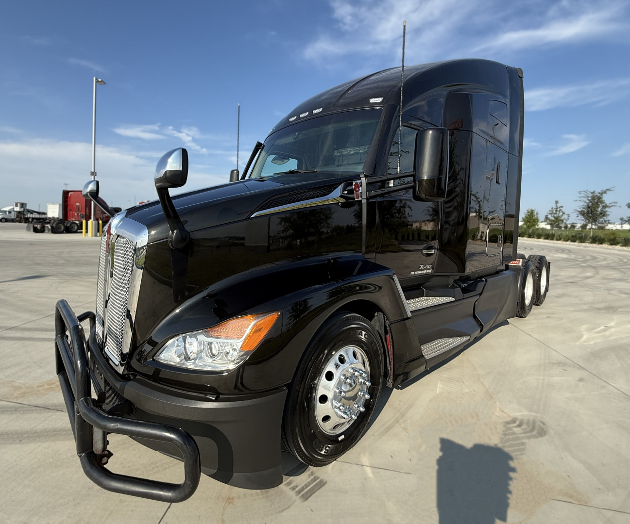 Kenworth T680 exterior front-left view showing polished chrome bumper, dual side mirrors, and black tractor with sleeper cab.