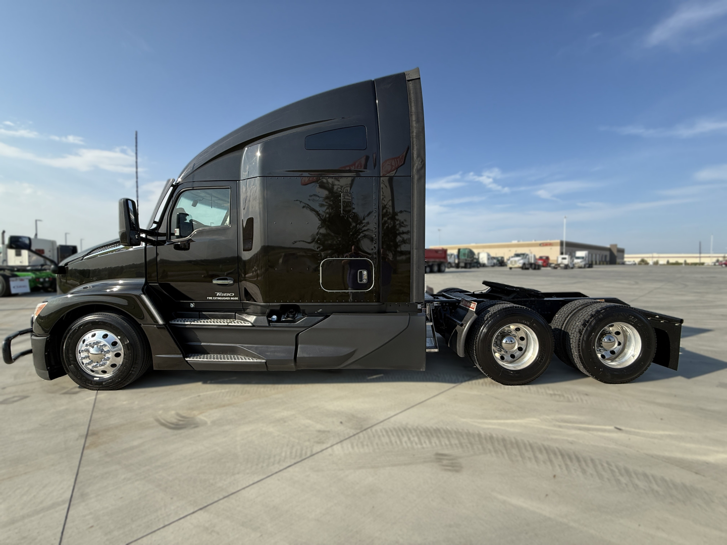 Kenworth T680 day cab tractor in black, side profile view showing sleeper cab, fuel tanks, and dual rear axles.