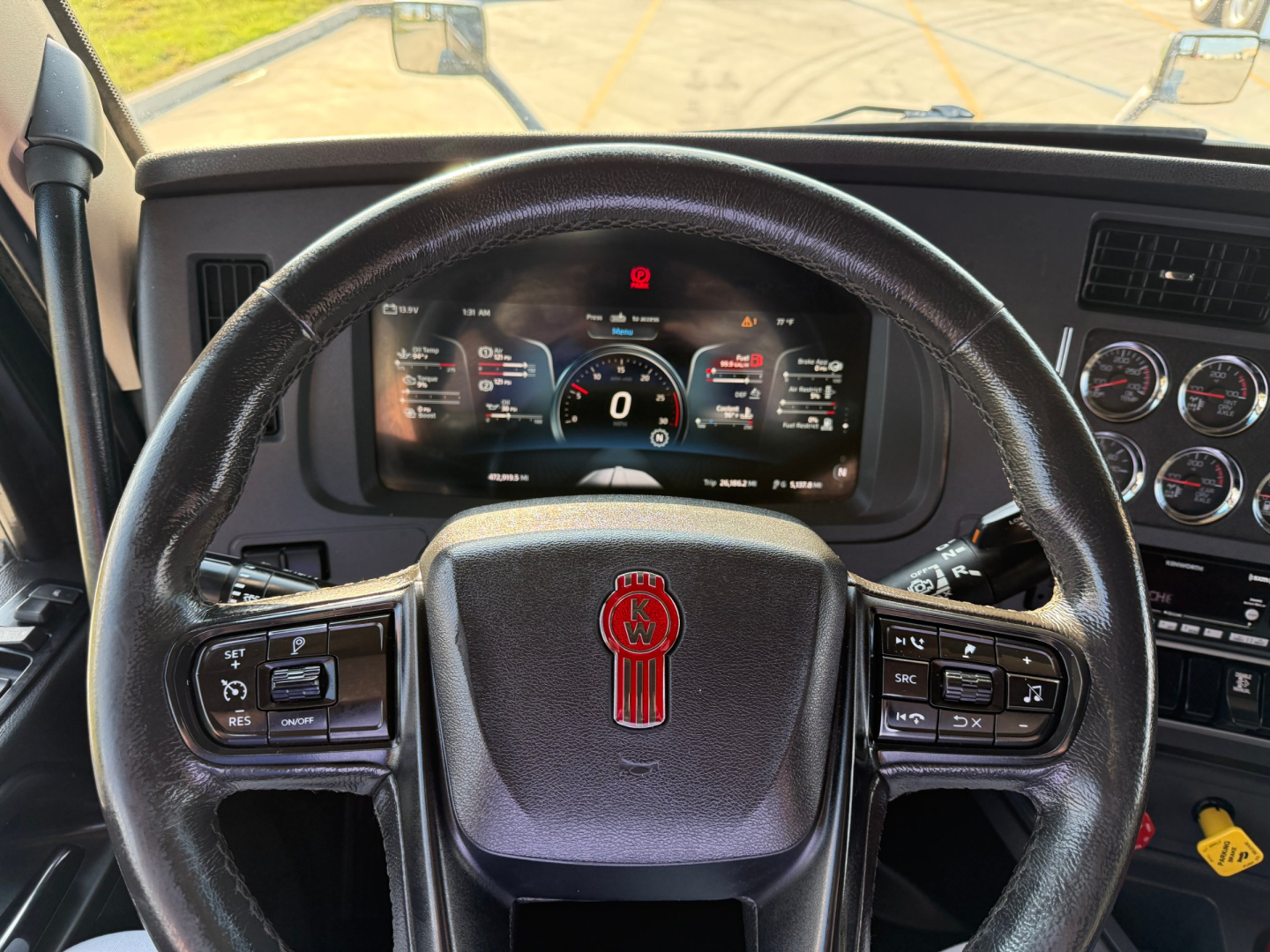 Kenworth T680 steering wheel and dashboard view showing digital gauge cluster in a truck cab.