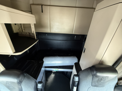 Kenworth T680 cab interior view showing sleeper area and entry steps; includes storage compartments and dark seating surfaces.