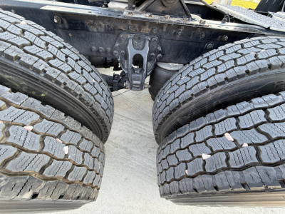 Kenworth truck dual rear axles with heavy-duty tires and suspension components visible between the tires.