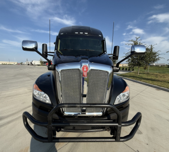 Front view of a black 2023 Kenworth T680 semi-truck with a chrome grille, grille guard, and large bumper. Kenworth emblem visible on the grille; side mirrors extend outward.