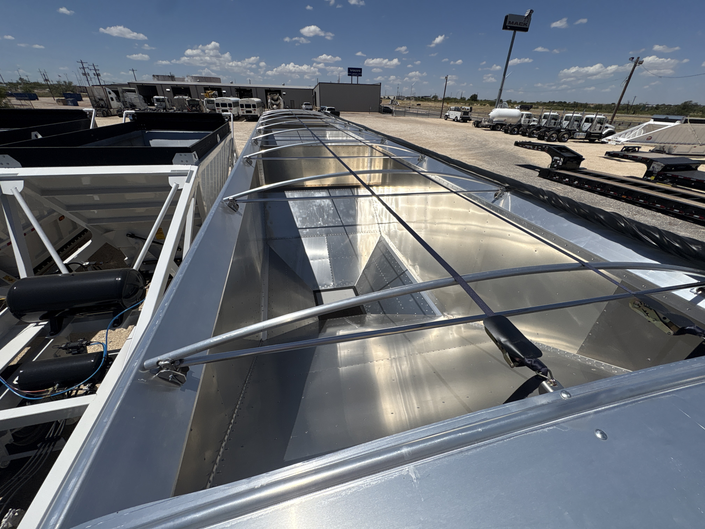 Aluminum grain hopper trailer top view showing corrugated sidewalls and protective steel grate with tank ribs and rails.