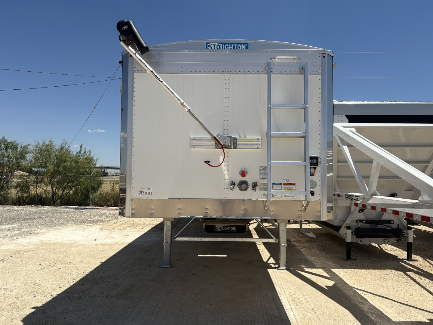 Stoughton 42' aluminum grain hopper trailer rear view with corrugated sidewalls and ladder, VIN 1DW1G4224VSC29165 displayed.