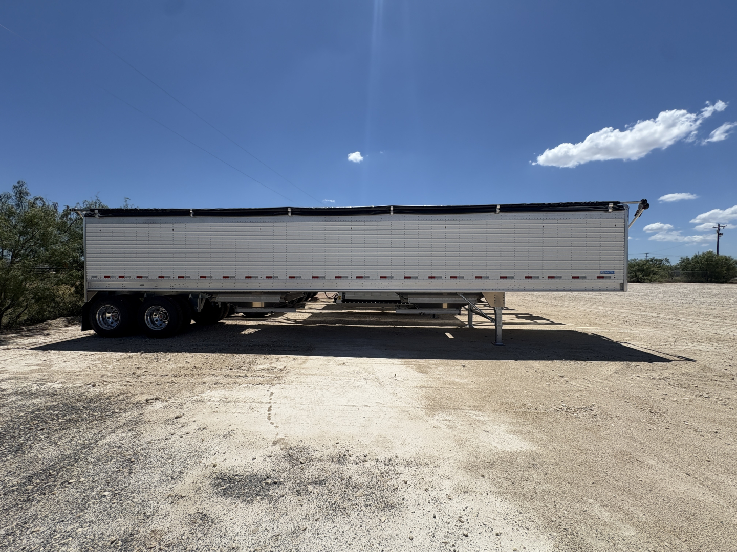 Trailer side view showing 42' aluminum grain hopper with 74" corrugated sidewalls on a dry lot.