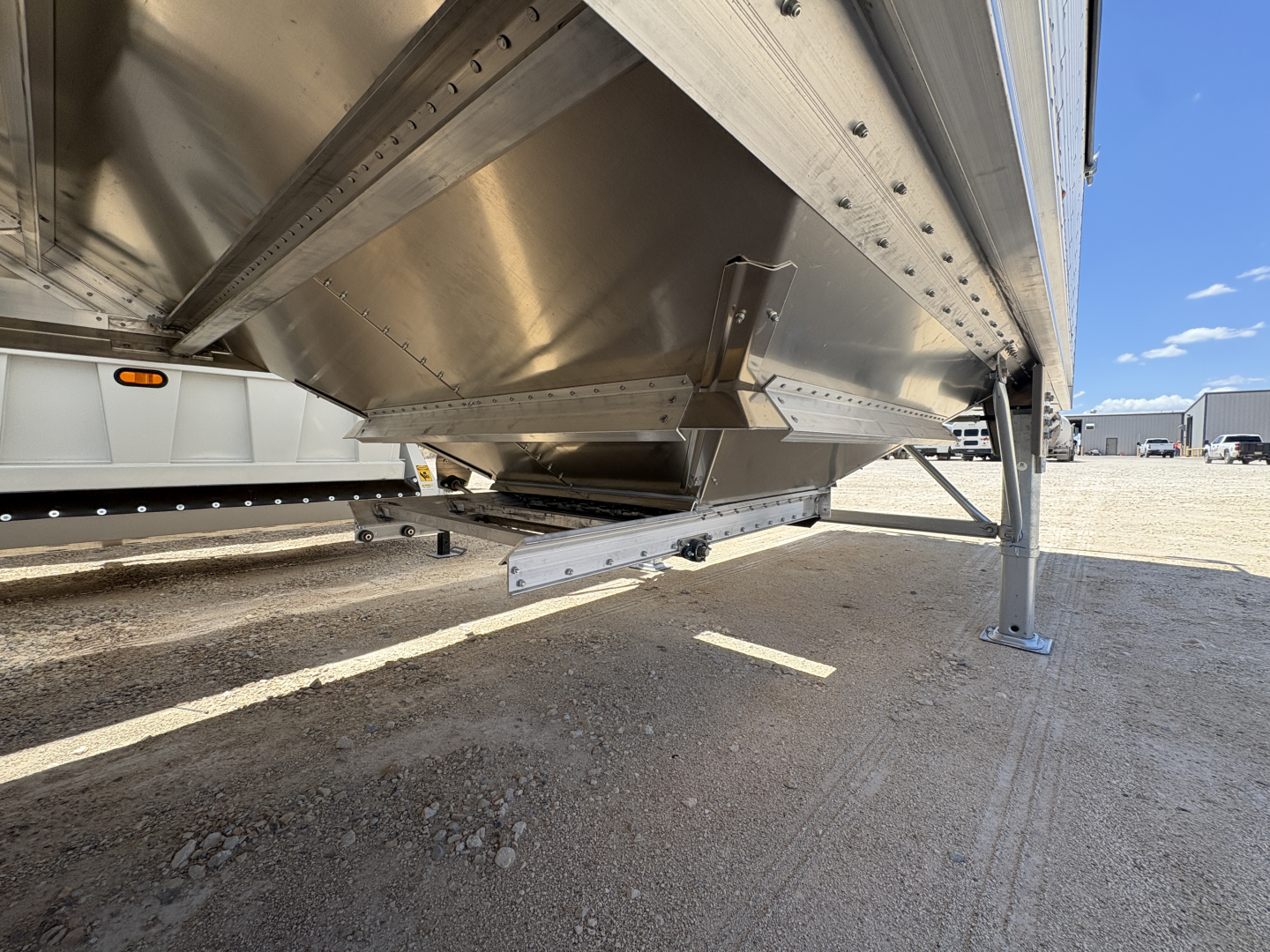 Trailer lower side view of a 42' aluminum grain hopper with 74 inch corrugated sidewalls showing the undercarriage, ladder leg, and corrugated sheet metal structure.