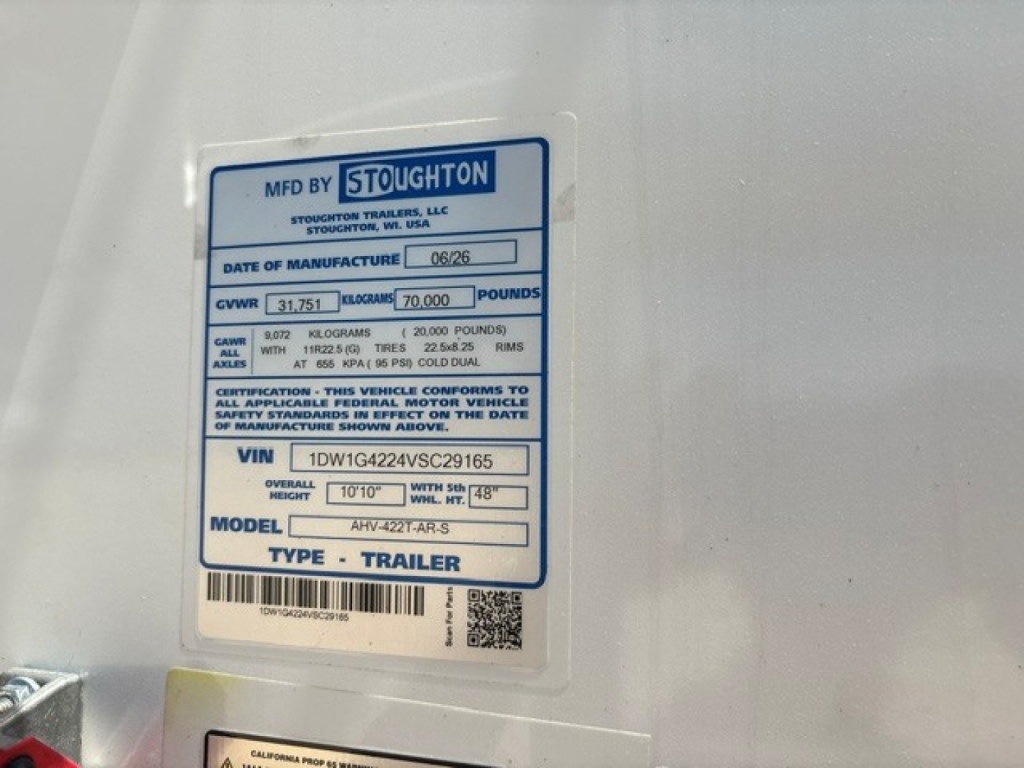 Stoughton trailer VIN sticker on white grain hopper showing GVWR, GAWR, model, and manufacture date. Close-up label includes ‘MFD BY STOUGHTON’ and VIN 1DW1G4224VSC29165.