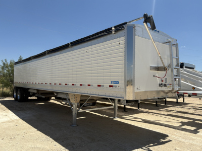 Trailer side view showing 42' aluminum grain hopper with corrugated sidewalls and rear access, VIN plate, and support legs visible.