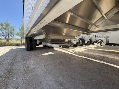 Stoughton 42' aluminum grain hopper trailer underside view showing corrugated sidewalls, framework, and wheels.