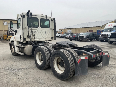 Freightliner Cascadia125 tractor at a lot, side rear view showing dual rear axles, fifth wheel, and mud flaps.