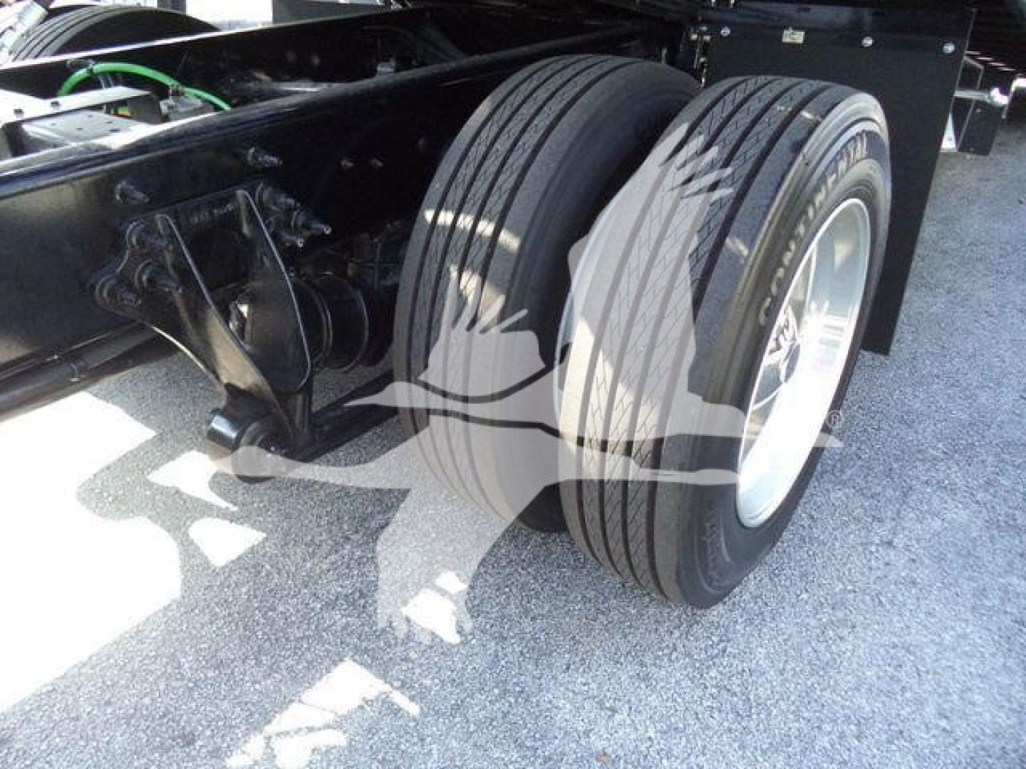 Dual rear tires on a new 2027 International MV roll-back truck chassis showing dual rear wheels, suspension components, and frame with wiring nearby.