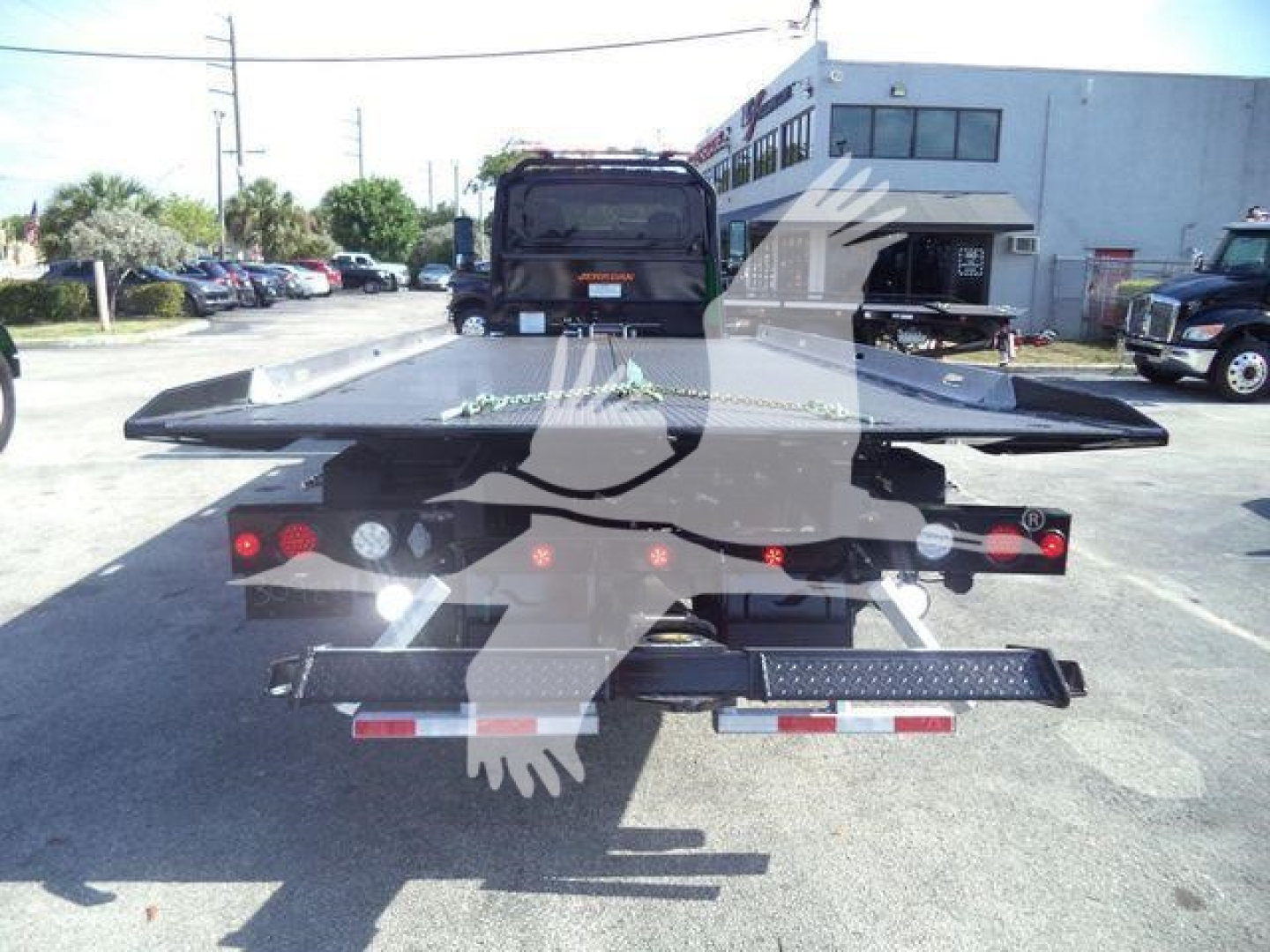 Tow truck equipment showing a flatbed rollback bed with rear lights and hydraulic assembly.