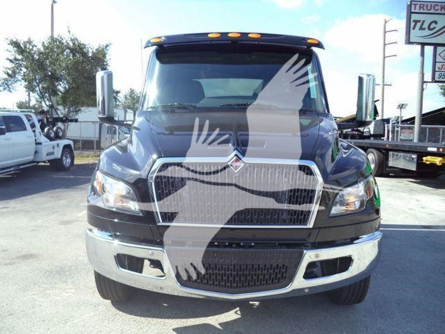 Front view of a black 2027 International MV truck showing chrome grille, bumper, and large side mirrors.