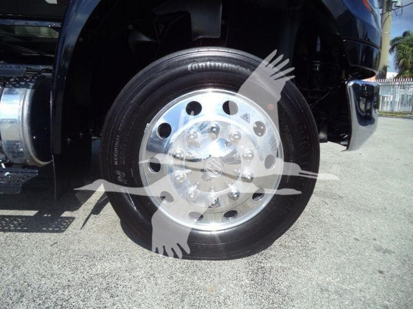 Truck front wheel showing polished chrome hub and black tire with visible white lettering on sidewall.