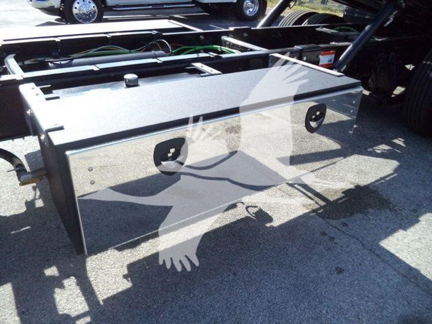 Truck bed toolbox mounted behind cab on a new 2027 International MV rollback truck, with two circular cutouts and metal panels.