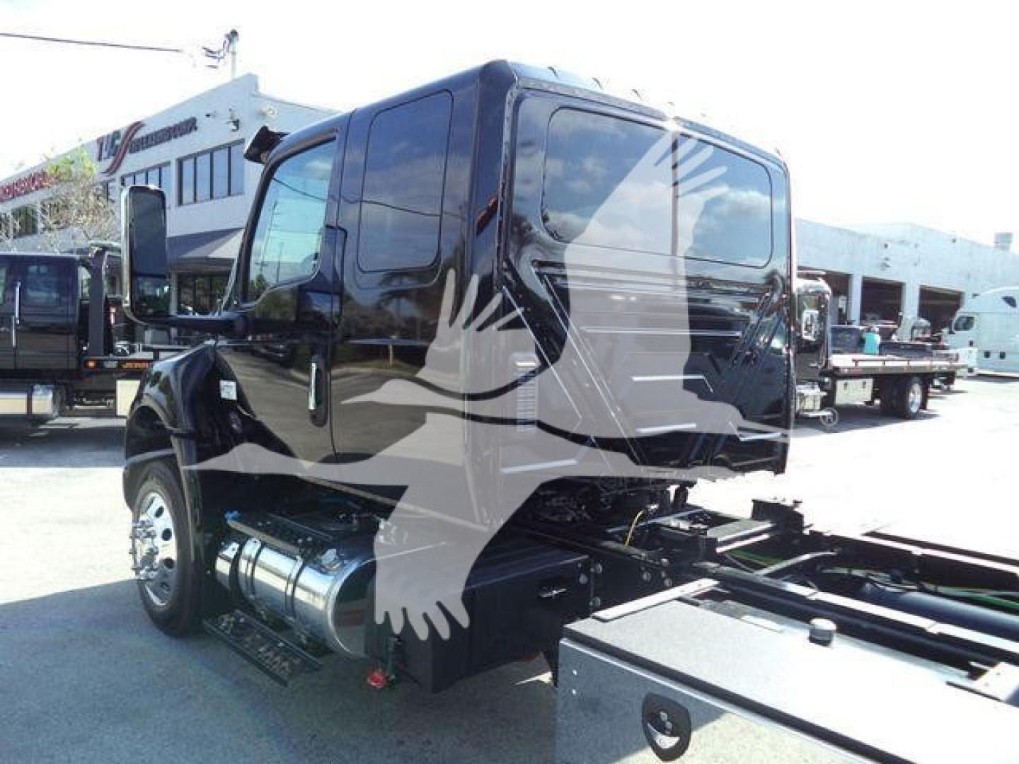 Truck cab side and rear view showing International MV chassis with black exterior and dual fuel tanks.