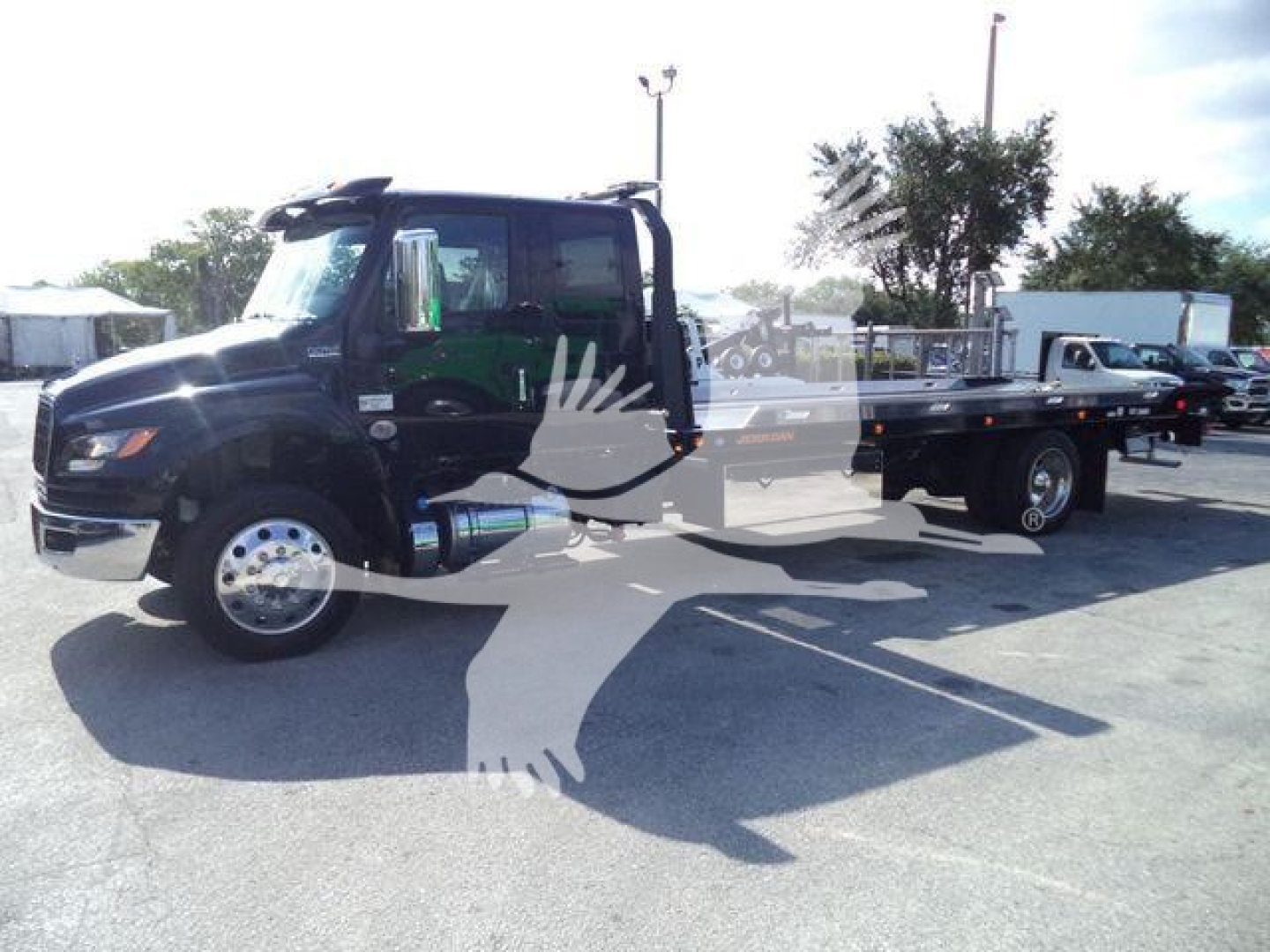 Truck cab and flatbed rollback showing International MV chassis with enclosed cab and long flatbed.