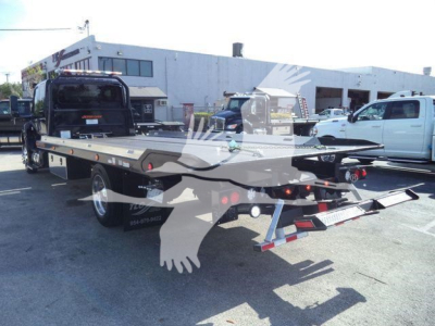 Flatbed tow truck in a dealership lot showing MVEXCABBLKSHRKFM stock unit with a black flatbed and rear dual ramps.