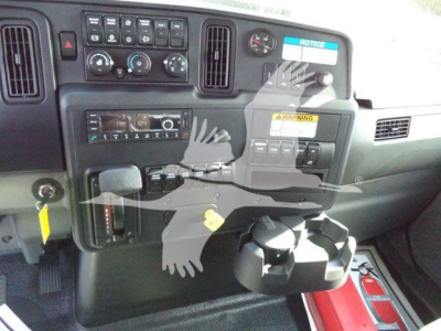 Truck dash cluster showing radio, climate controls, and cup holders; dashboard includes warning labels and various switches; reflection of scissors watermark overlay.