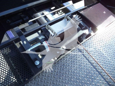 Truck rollback equipment mount with metal chains and hydraulic components visible on a diamond plate surface.