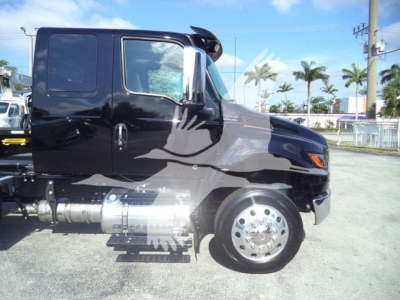 Truck cab with black paint and chrome fuel tanks showing side view of International MV cab and wheel assembly.