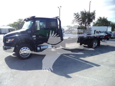 Truck cab and flatbed rollback showing International MV chassis with enclosed cab and long flatbed.