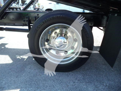 Truck wheel and undercarriage showing a shiny metal wheel with hubcap and black tire; faint watermark of hands across the image.