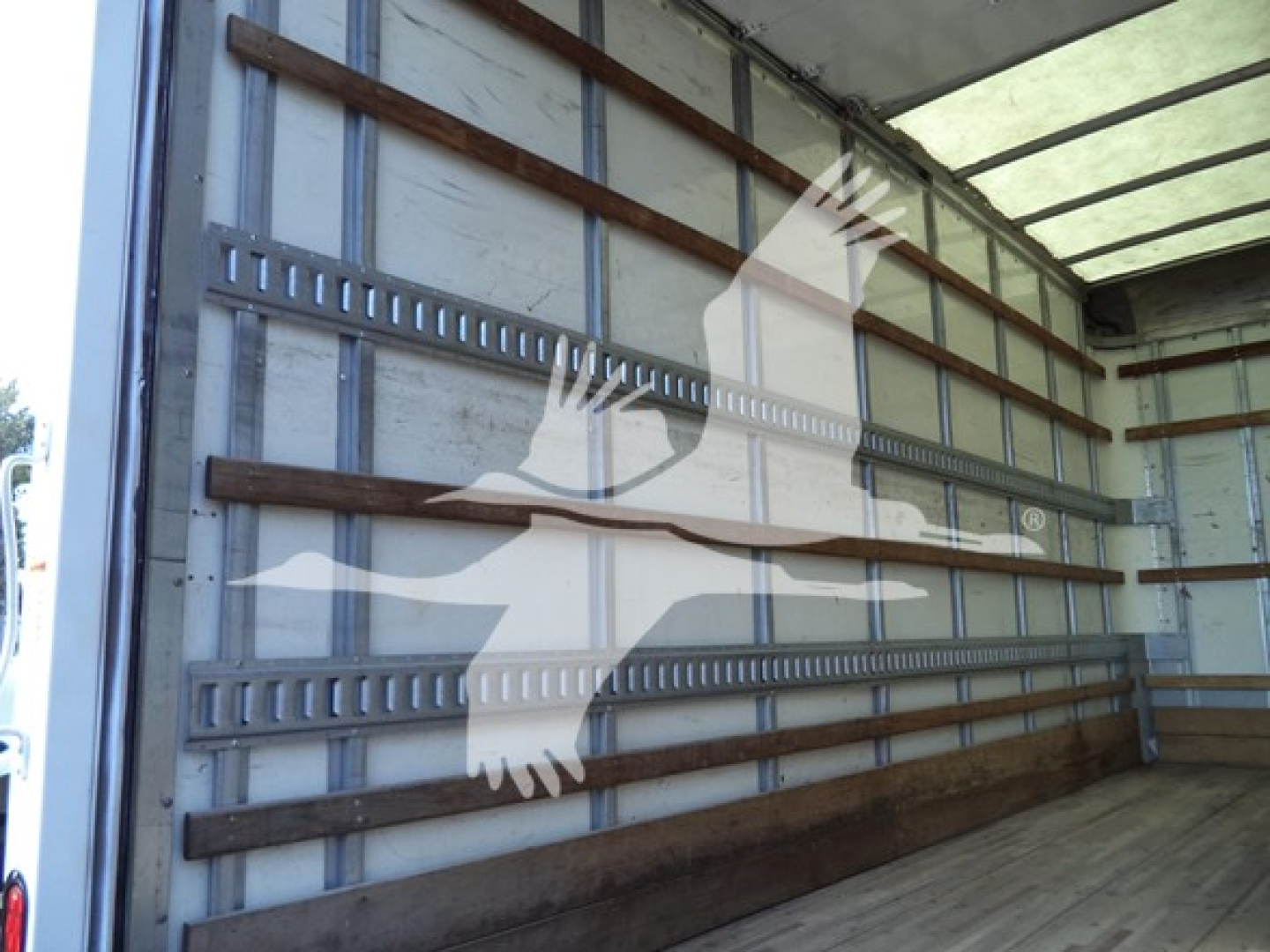 Inside view of a box truck cargo area with striped wooden side rails and metal track slats.