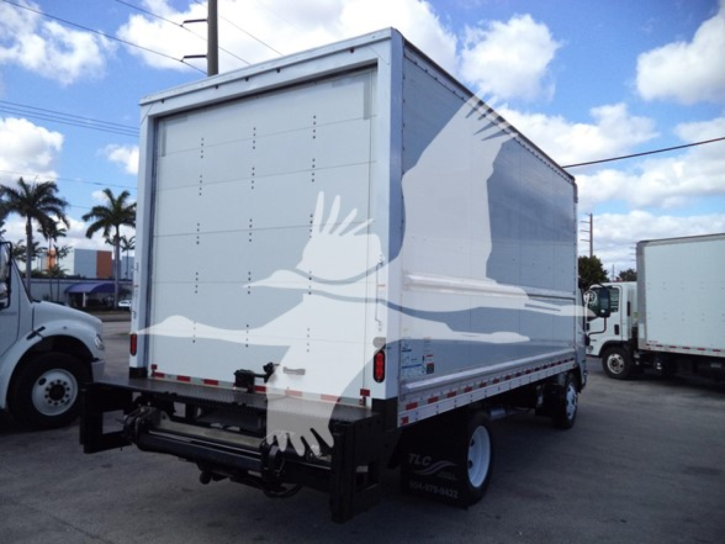 Isuzu NPR HD box truck rear view showing cargo box and back doors with white graphic of flying geese overlay