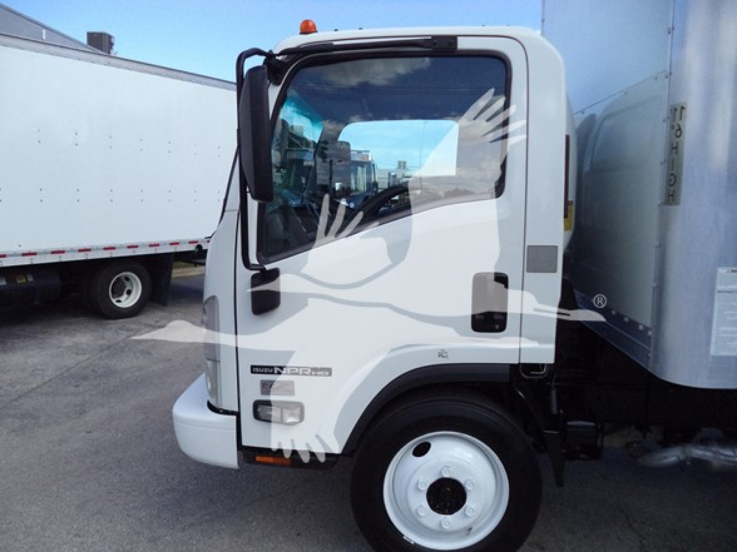Isuzu NPR-HD box truck cab with white exterior, door badge and side mirrors visible; window reflects hands.
