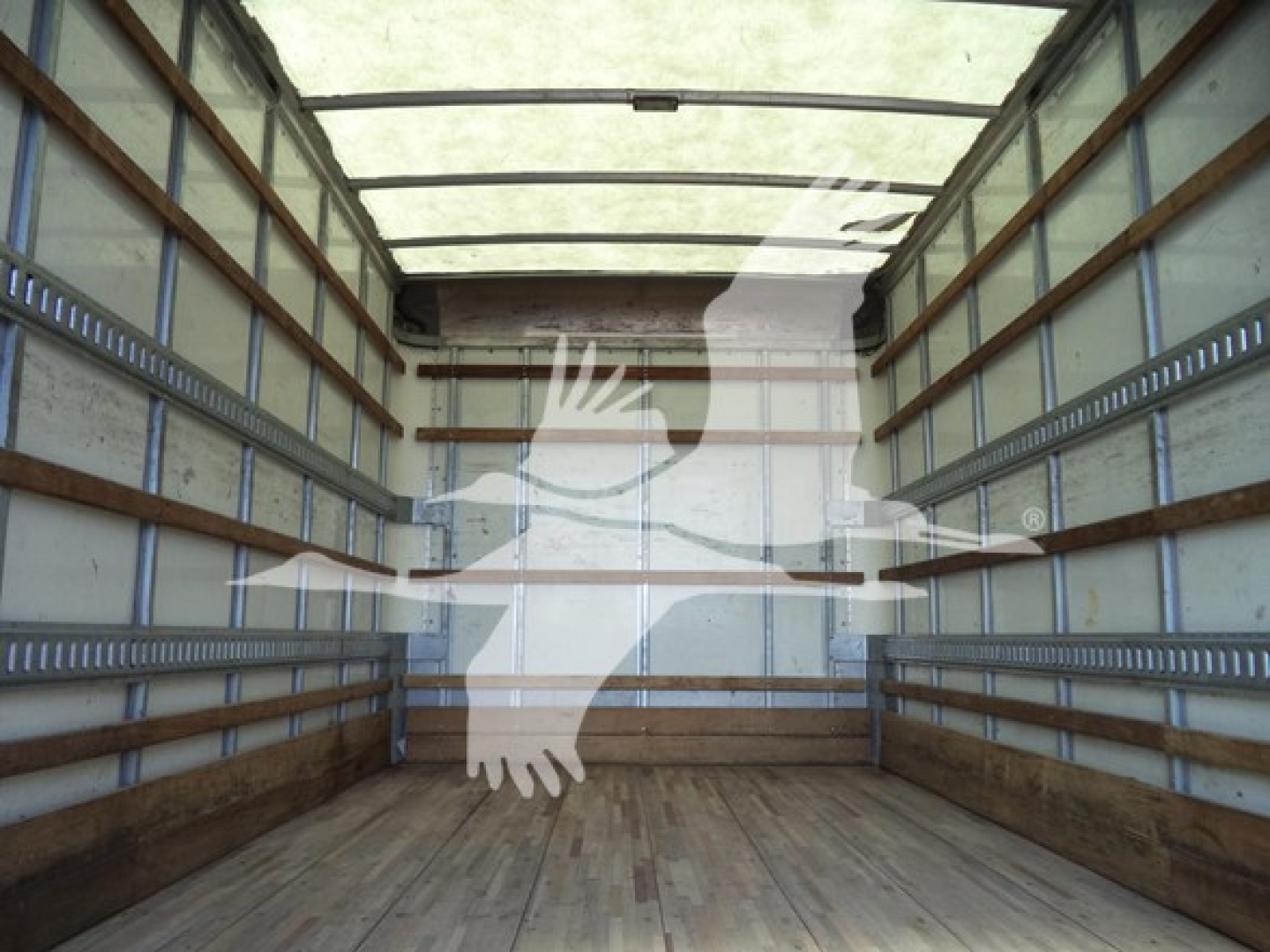 Truck cargo area interior with wooden floor and metal side walls, slight reflections of a person climbing image overlayed.
