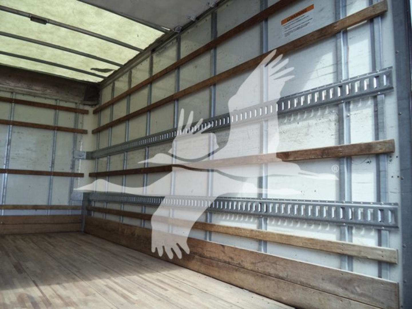Isuzu NPR-HD box truck interior showing wooden side rails and metal tracks along wall, empty cargo area.