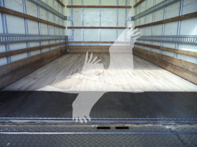 Isuzu NPR HD box truck interior cargo area with wooden floor and metal side rails; empty at rear showing cargo area and ramp edge.