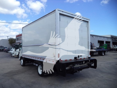 Isuzu NPR HD box truck rear/side view with closed cargo box and bumper hitch in a dealership lot.